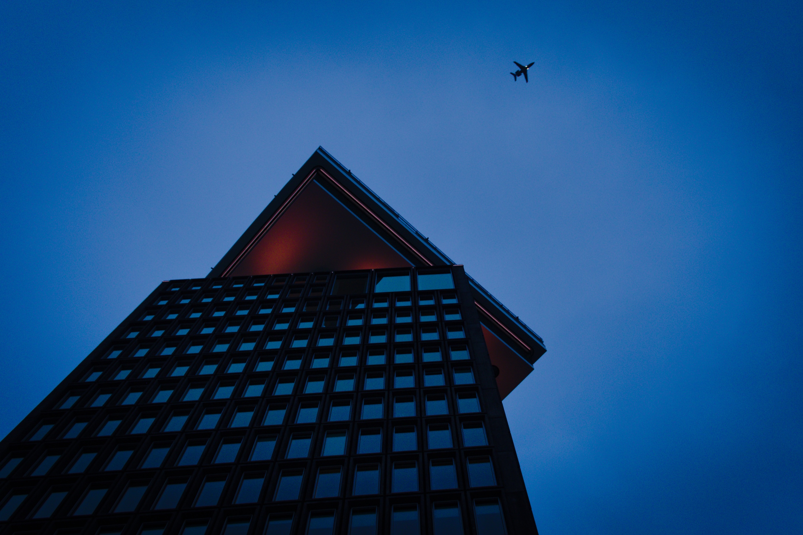 Airplane above a geometric building at blue hour