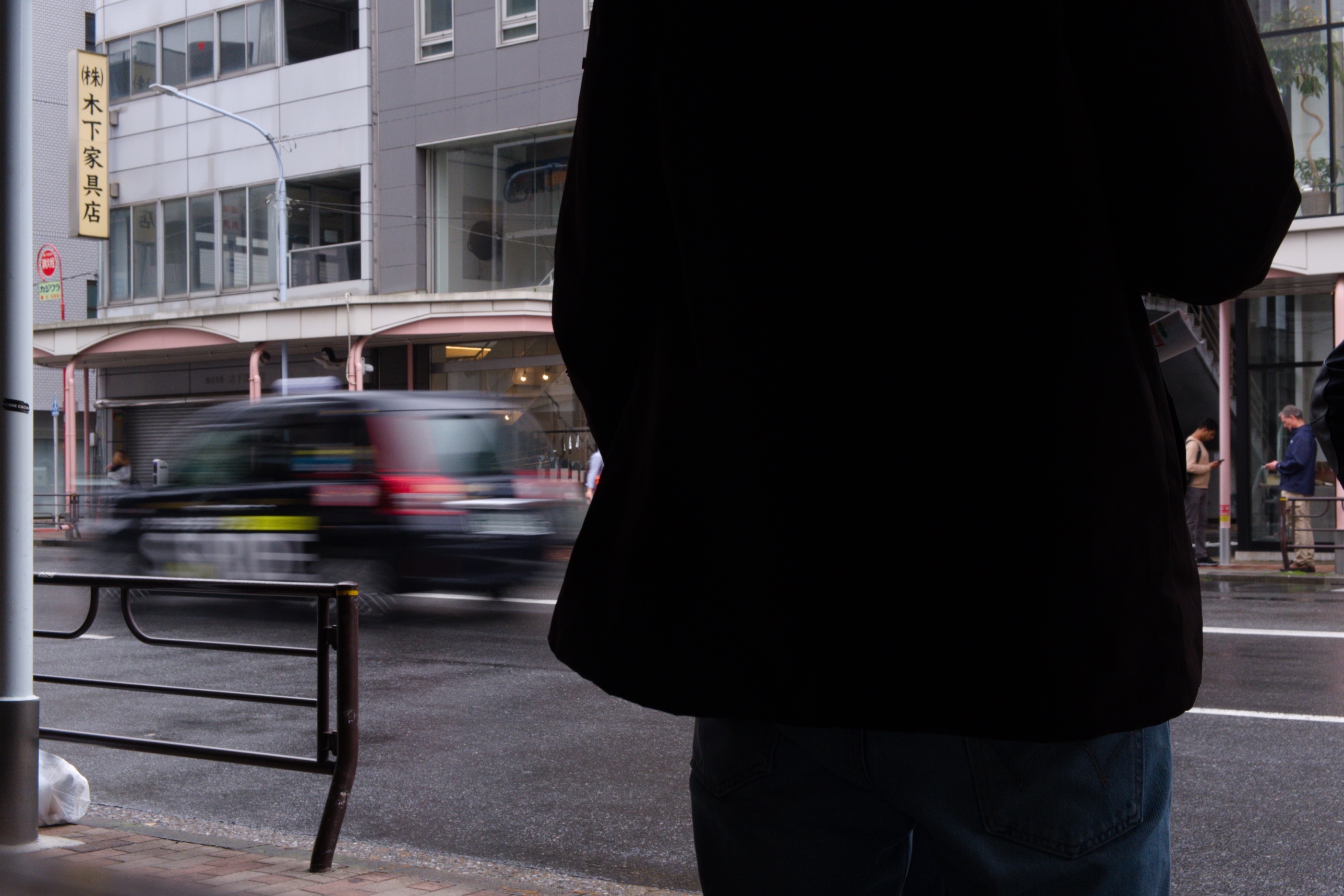 Silhouetted figure and a moving taxi on a Tokyo street